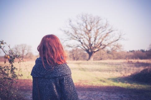 A young woman with red hair is walking in the countryside on a winter day