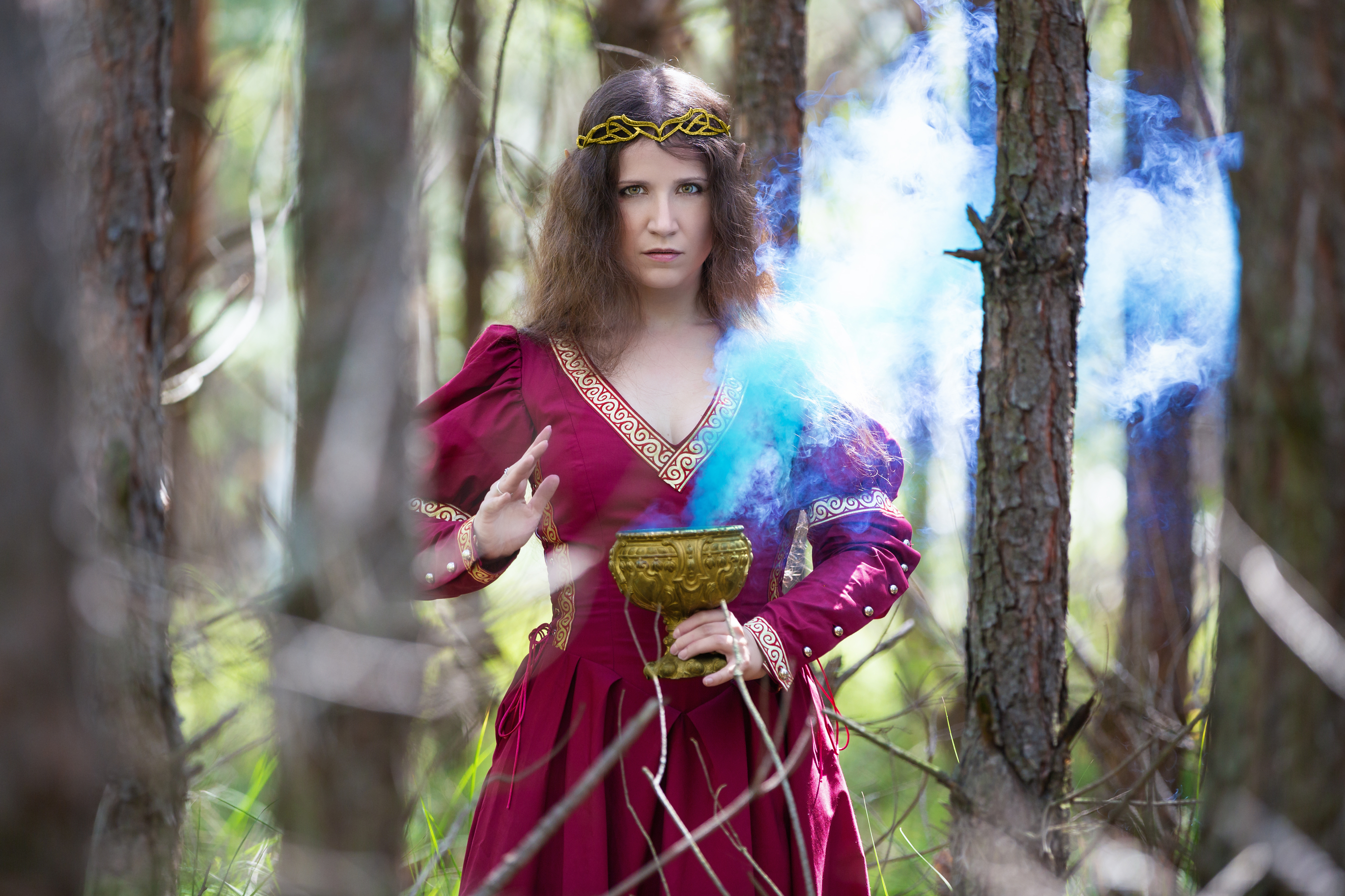 Woman in a red dress casting a spell with smoke