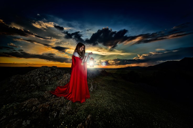 beautiful woman with red cloak in the sunset light