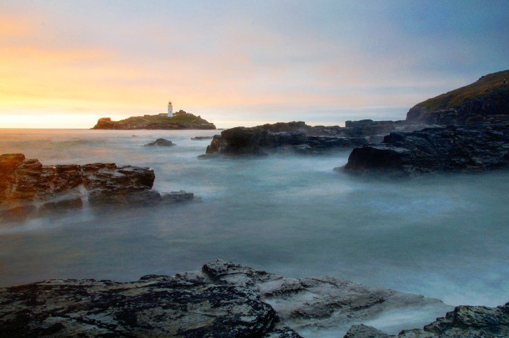 Misty lighthouse at sunrise sunset